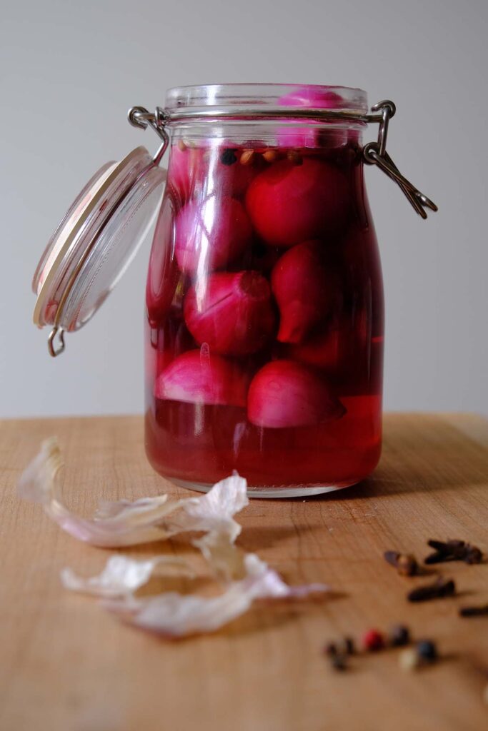 A glass jar with pickled pink cocktail onions