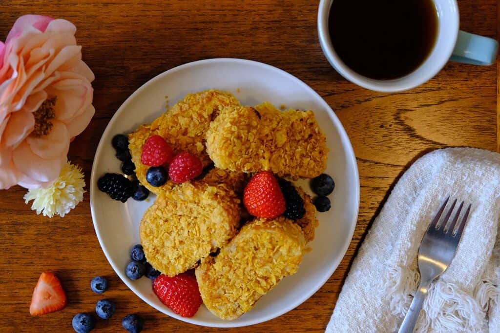 Top-down view of crispy French toast with cornflake coating and a colorful mix of fresh berries.
