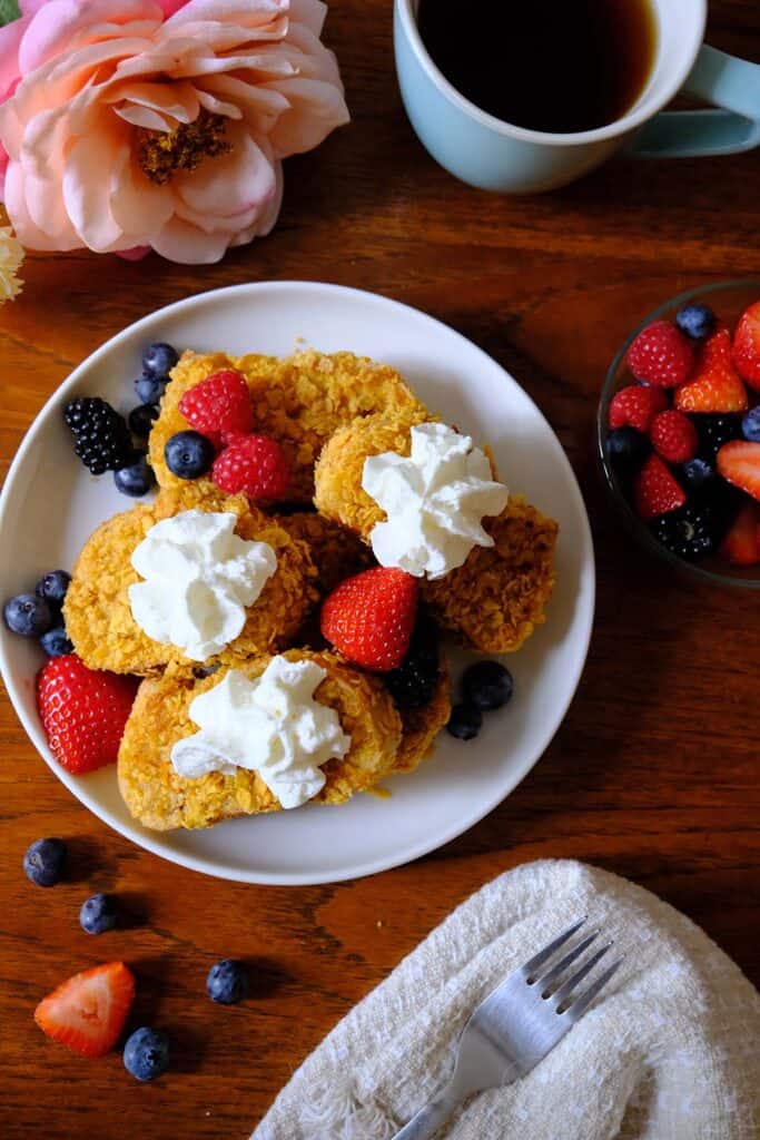 Crispy French toast recipe plated for brunch with fresh fruit and a mug of coffee on a wooden table.