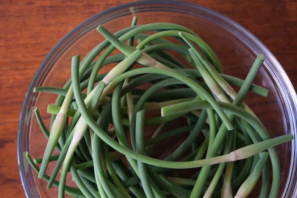 Garlic Scapes in a clear glass bowl on a wooden table