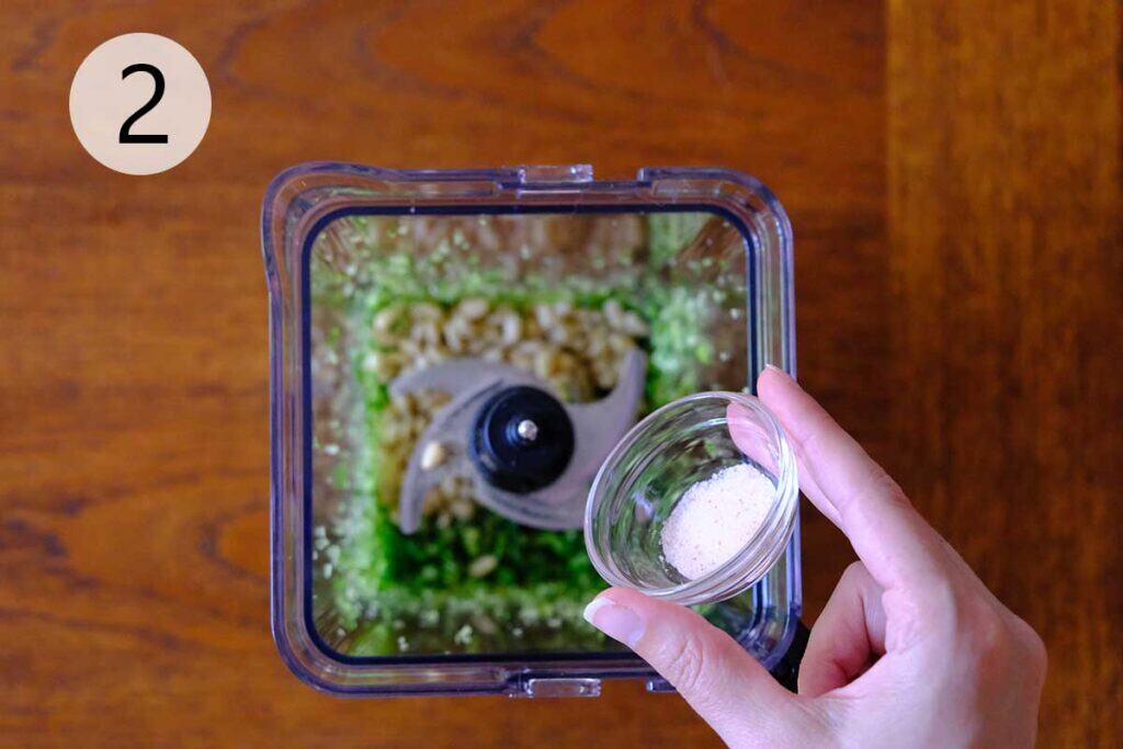 Steps to make this garlic scape pesto recipe - Pine nuts and lemon zest added to chopped garlic scapes in a food processor