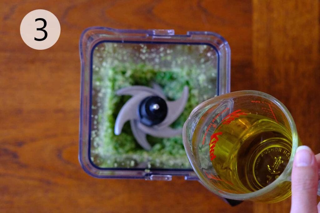 Steps to make this garlic scape pesto recipe - Garlic scape mixture blending with olive oil, salt, and pepper in food processor