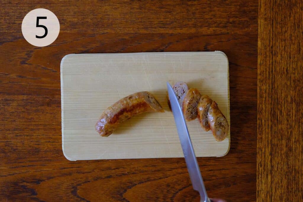 Sliced roasted sausage arranged on a cutting board, ready to be added to the pasta salad.