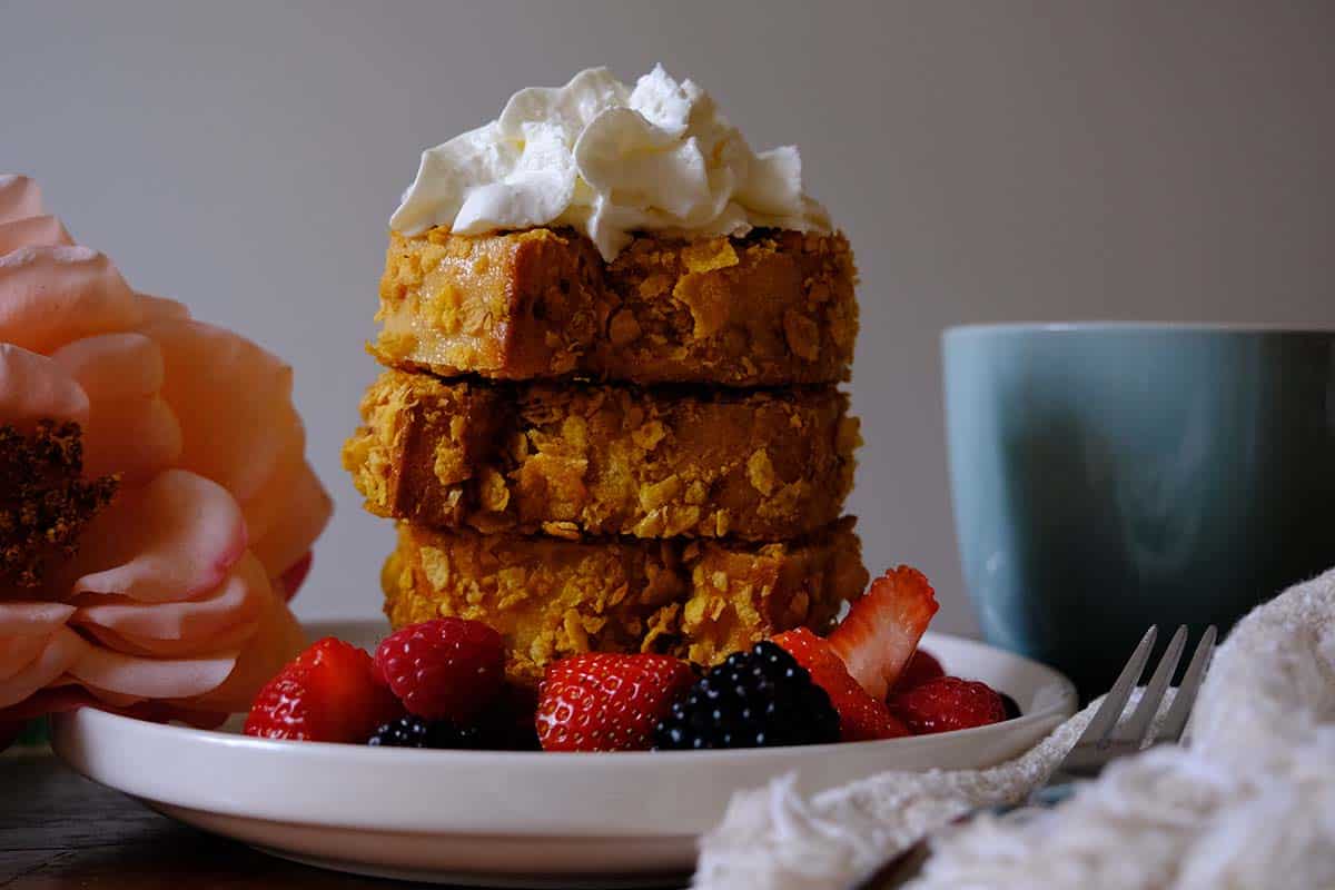 Close-up of crispy French toast recipe made with cornflakes, fresh fruit, and whipped cream for a weekend brunch.