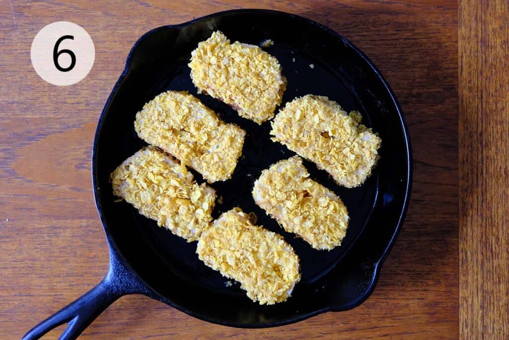 Cooking Cornflake Crispy French toast in a cast iron skillet on a wooden table