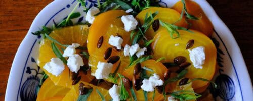 Vibrant golden beet salad recipe featuring sliced beets, citrus, goat cheese, and tarragon on a serving dish.