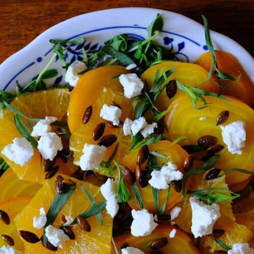 Vibrant golden beet salad recipe featuring sliced beets, citrus, goat cheese, and tarragon on a serving dish.