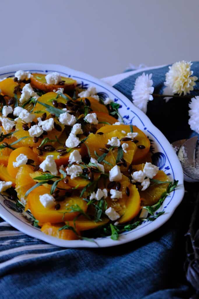 Colorful vegetarian golden beet salad garnished with fresh herbs, toasted seeds, and crumbled cheese.