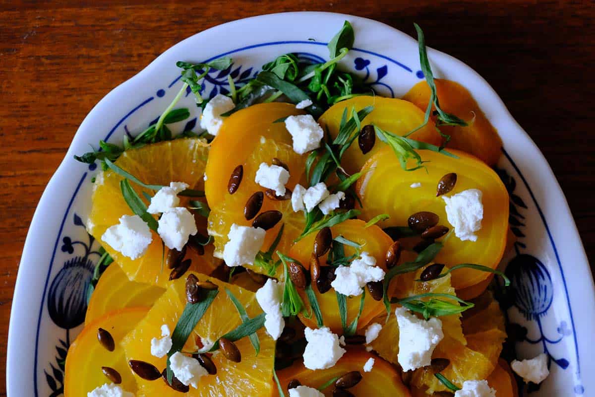 Vibrant golden beet salad recipe featuring sliced beets, citrus, goat cheese, and tarragon on a serving dish.
