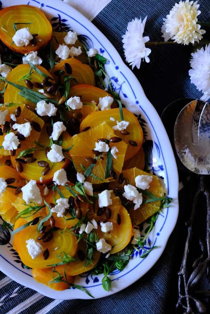 Close-up of a citrus and tarragon golden beet salad topped with pumpkin seeds and goat cheese crumbles.
