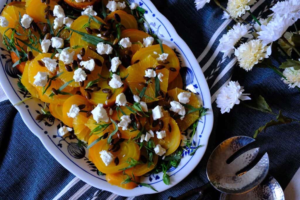 Colorful vegetarian golden beet salad garnished with fresh herbs, toasted seeds, and crumbled cheese.