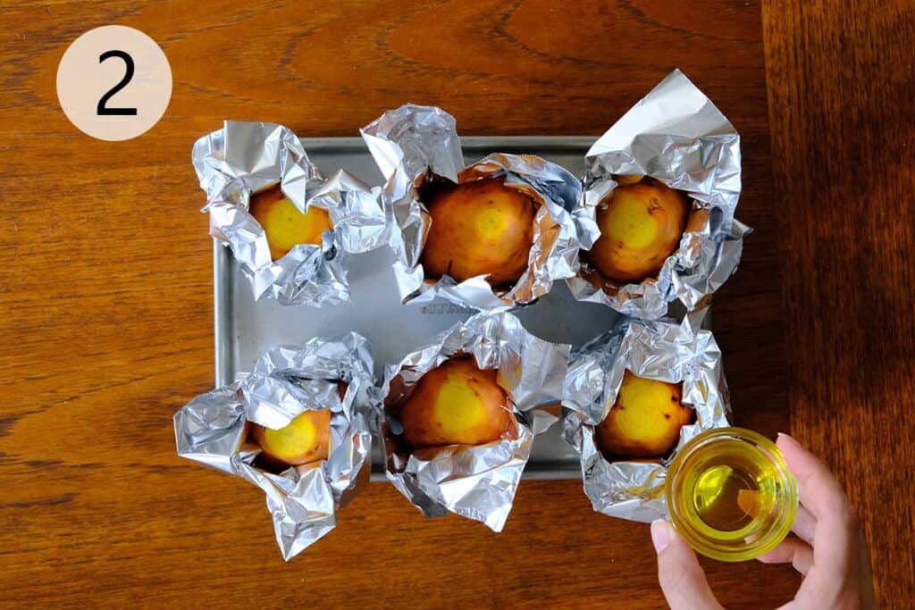 Golden beets drizzled with oil and wrapped in foil, ready for roasting, arranged on a rustic wooden surface.