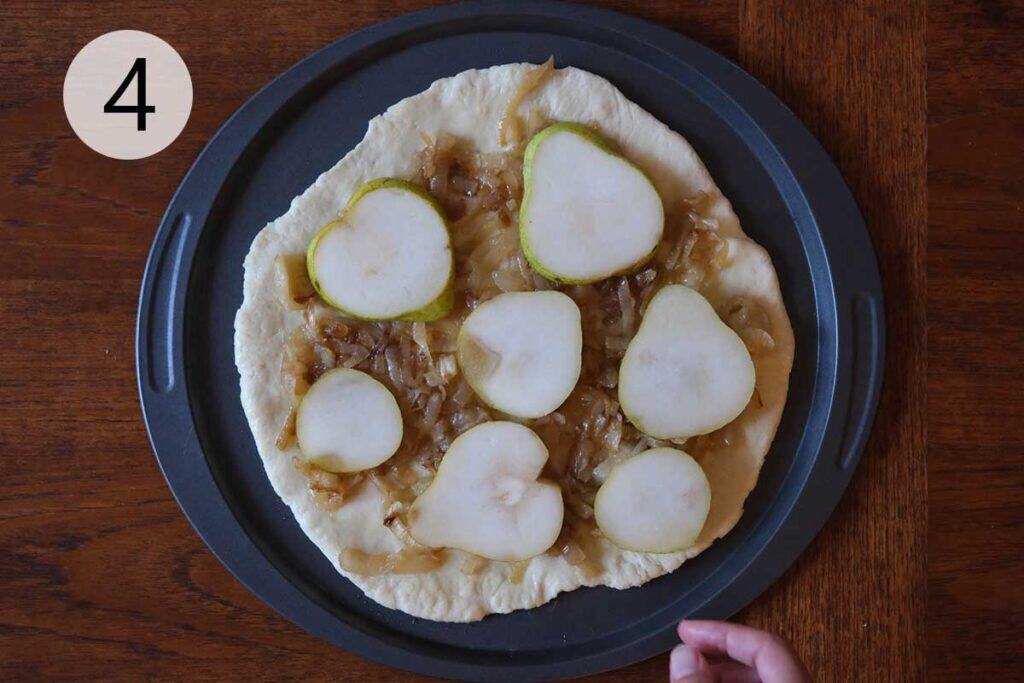 Instructions to make this pear pizza recipe - step four covering pizza dough in sliced pears