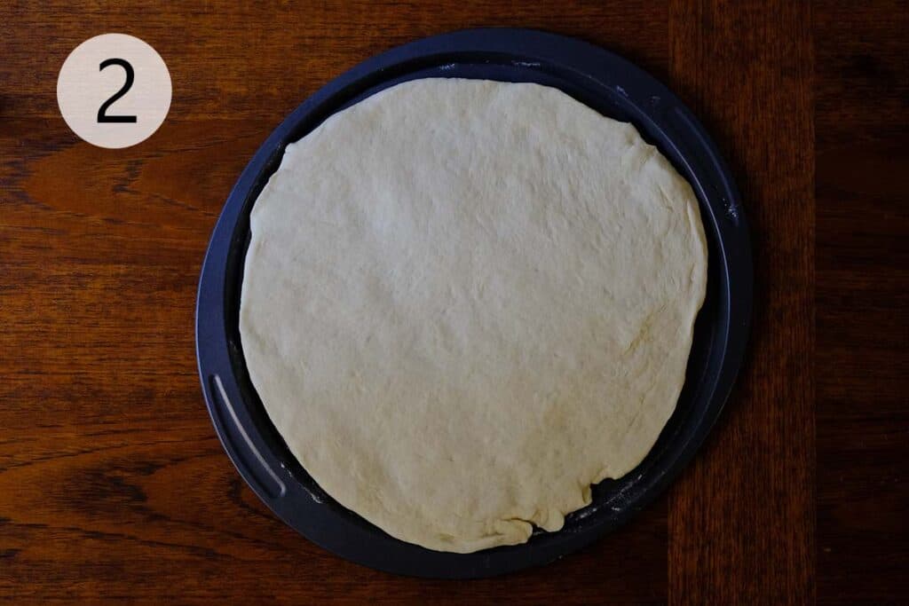 pizza dough stretched into a thin Neapolitan-style crust on a baking tray