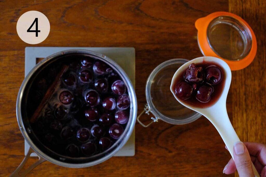 Cooked Luxardo cherries and syrup being ladled into a clean mason jar for cooling and storage.