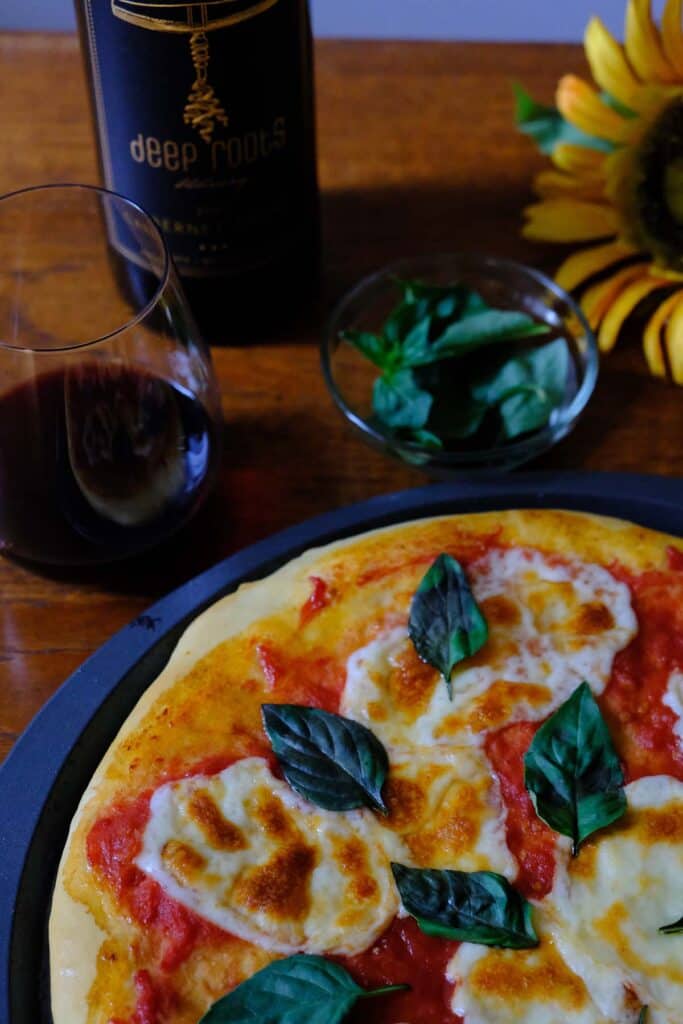 Traditional Italian Margherita pizza hot from the oven, plated with a glass of wine