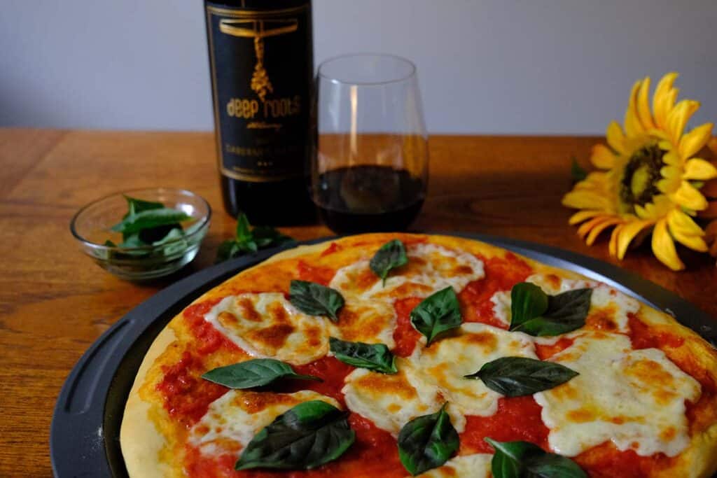 Easy Margherita pizza with crispy crust and fresh ingredients, styled on a wooden table with red wine