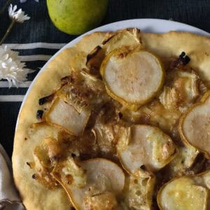 Golden crust pear pizza recipe topped with sliced pears, brie, and onions