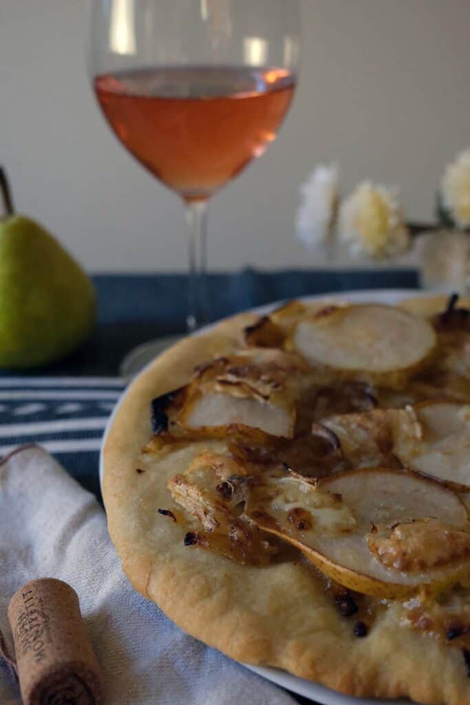 Upscale pear pizza recipe shown with wine glass and rustic table setting – ideal for entertaining or cozy nights.