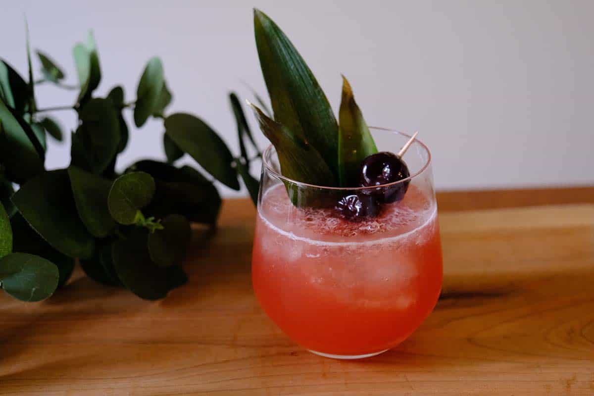 Tropical Shark's Tooth Cocktail in a clear glass with bold garnish, crushed ice, and a float of Jamaican rum.