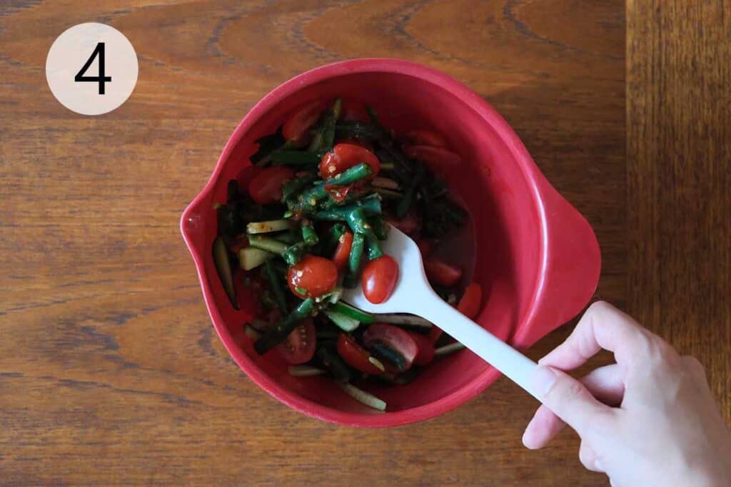 Mixing cucumber and cherry tomatoes with spicy Thai chili dressing.