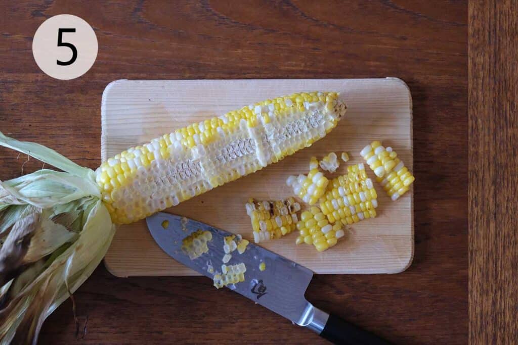 Slicing kernels off a grilled corn cob for Thai Corn Salad.