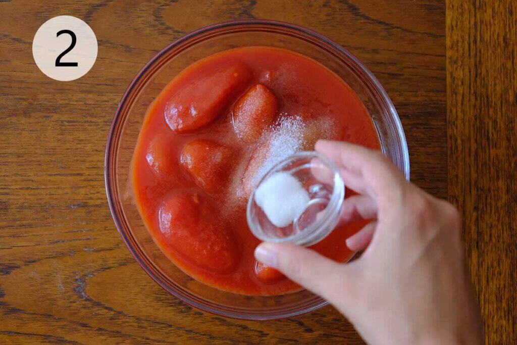 Stirring kosher salt into crushed San Marzano tomatoes to create a simple, authentic Italian Neapolitan pizza sauce.