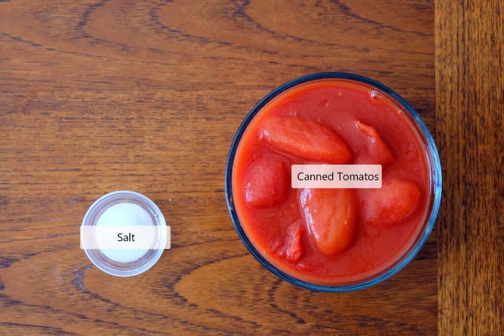 Top-down view of ingredients for Neapolitan Pizza Sauce Recipe: whole San Marzano tomatoes and kosher salt for fresh pizza flavor.