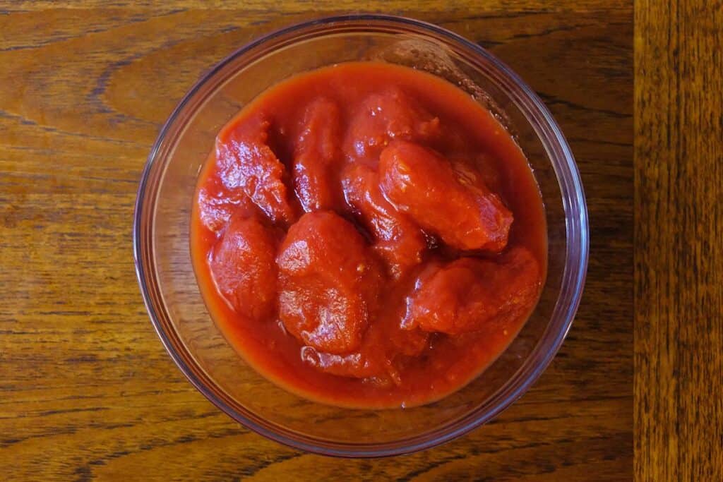 Top down view of San Marzano Tomatoes in a glass bowl on a wooden table