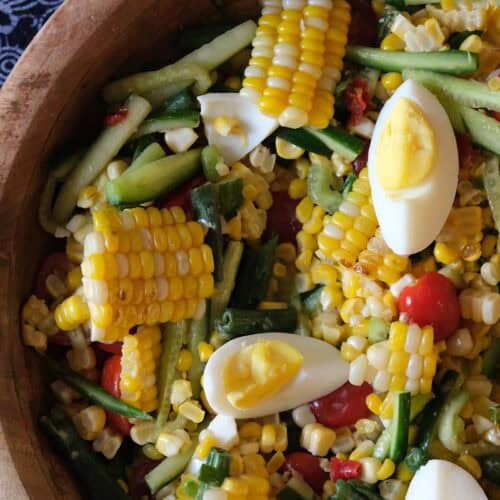 Close-up of Thai spicy corn salad with salted duck eggs, crunchy green beans, cucumbers, and cherry tomatoes, perfect with sticky rice and other Thai cuisines