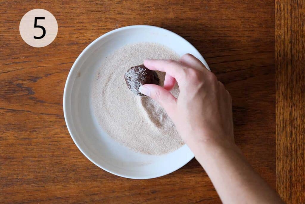 Rolling Mexican Chocolate Cookie dough balls in cinnamon sugar before baking.