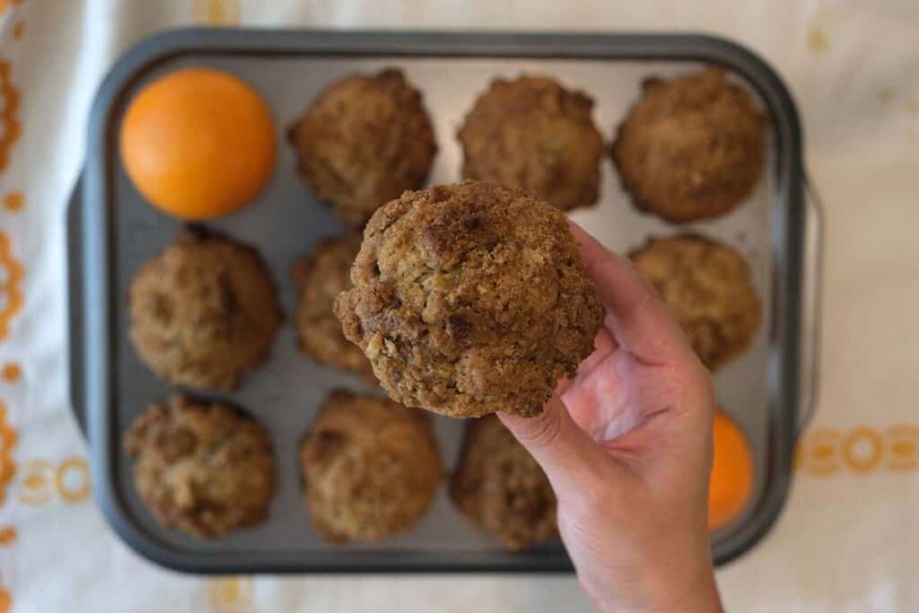 Freshly baked zucchini and orange muffin recipe with walnuts in a pan on a patterned tablecloth
