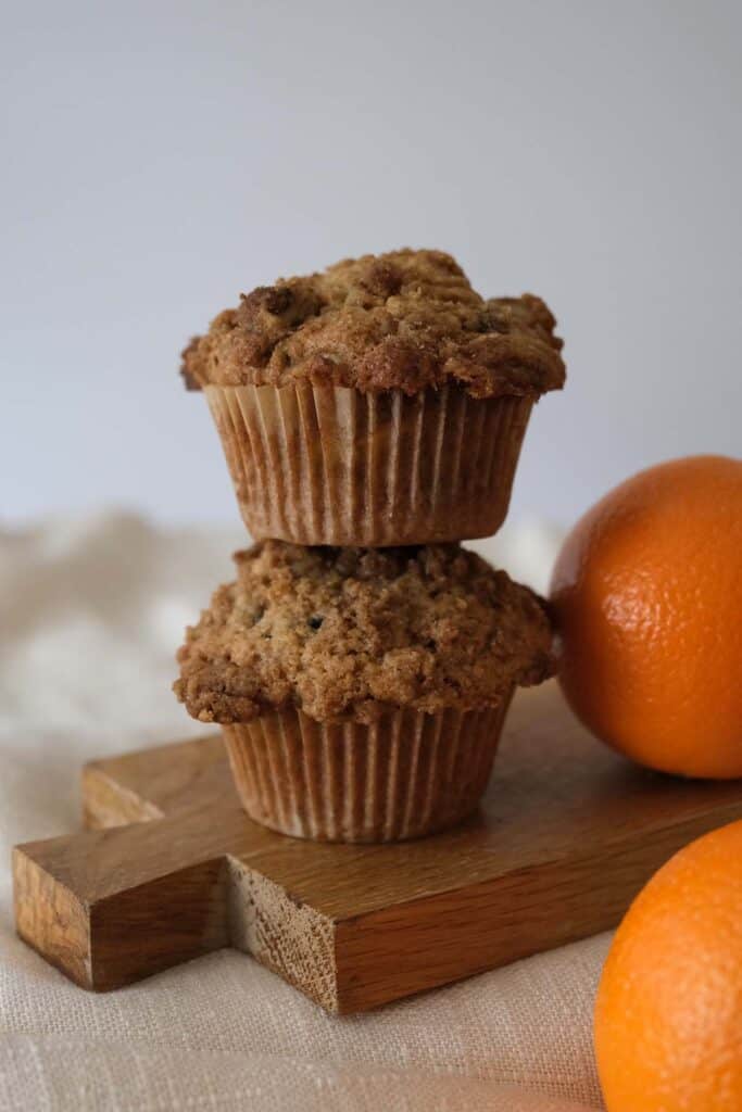 Bakery-style zucchini and orange muffins stacked with oranges, a perfect breakfast treat.