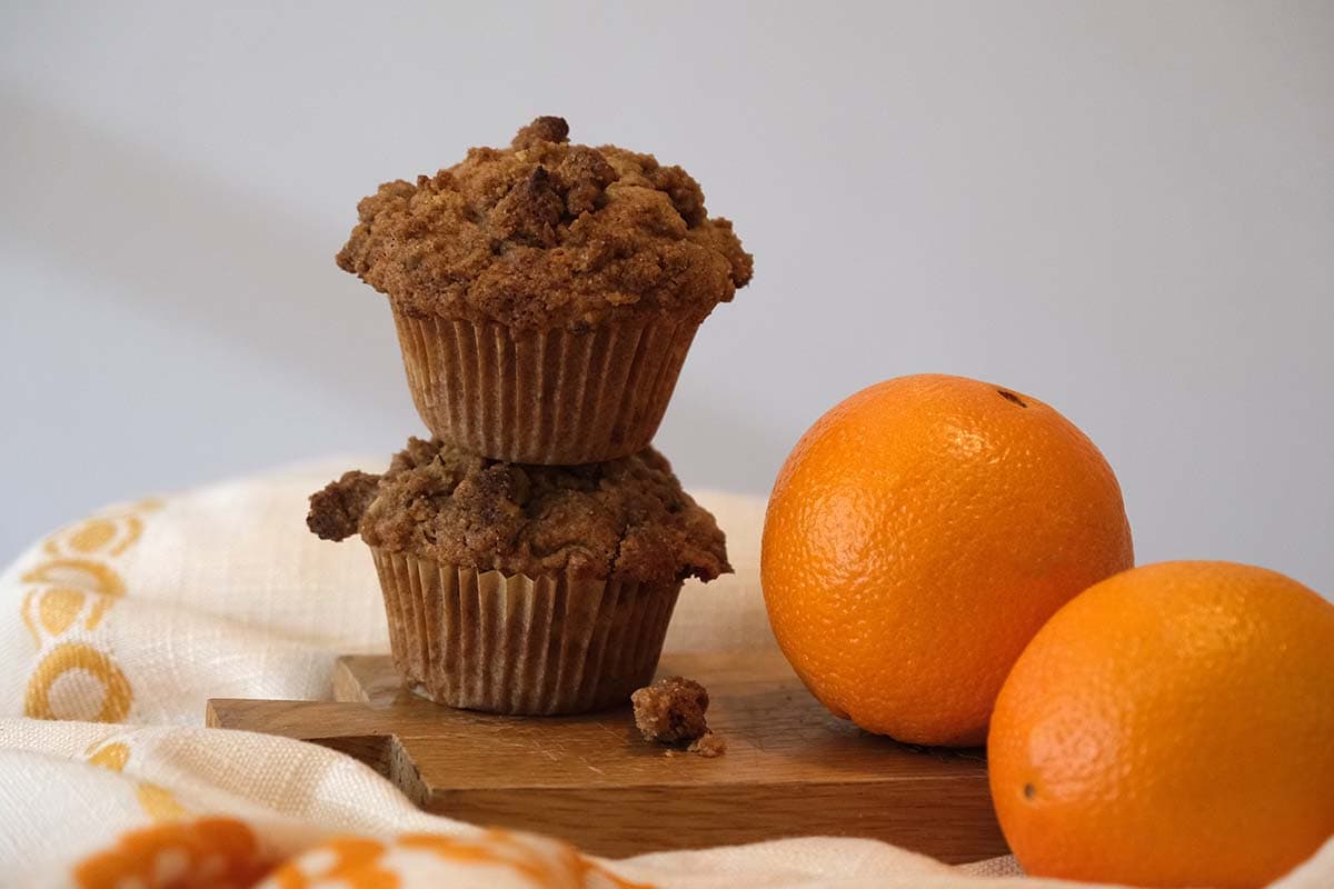 Homemade zucchini orange muffin recipe with cinnamon walnut crumb topping and fresh oranges.