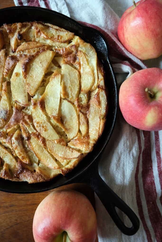 Homemade German Apple Pancake baked in a skillet with golden apple slices, ready to drizzle with maple syrup for a cozy weekend brunch.