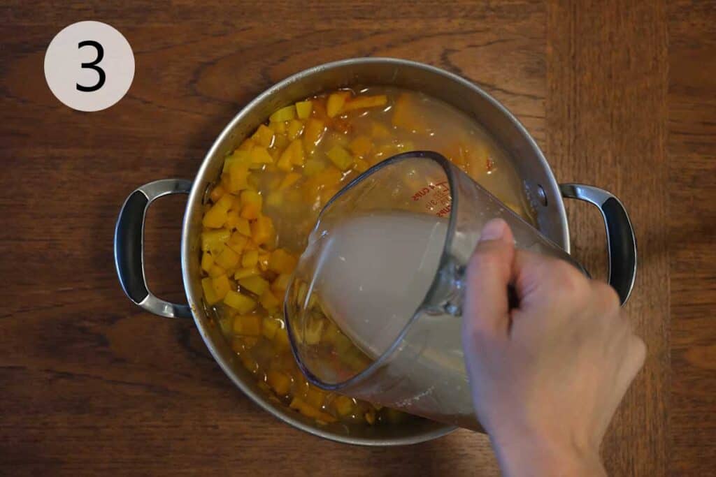 Roasted butternut squash and vegetable broth simmering in a soup pot, forming the rich and creamy base of Thai curried apple and butternut squash soup.