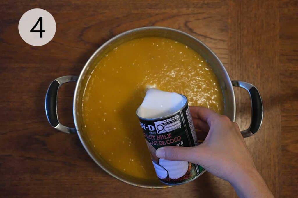 Adding creamy coconut milk to the already blended curried apple and butternut squash soup.