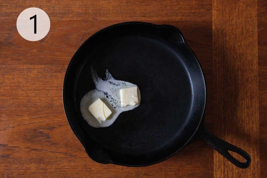 Hot cast iron pan with melted butter being swirled to coat the bottom and sides, ready for baking a golden German Apple Pancake.