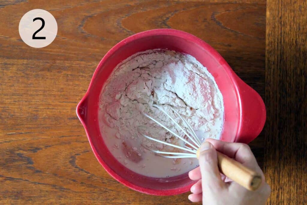 Whisking pancake batter in a large bowl until smooth and creamy for a German Apple Pancake Recipe. The base for a light and fluffy oven-baked pancake.