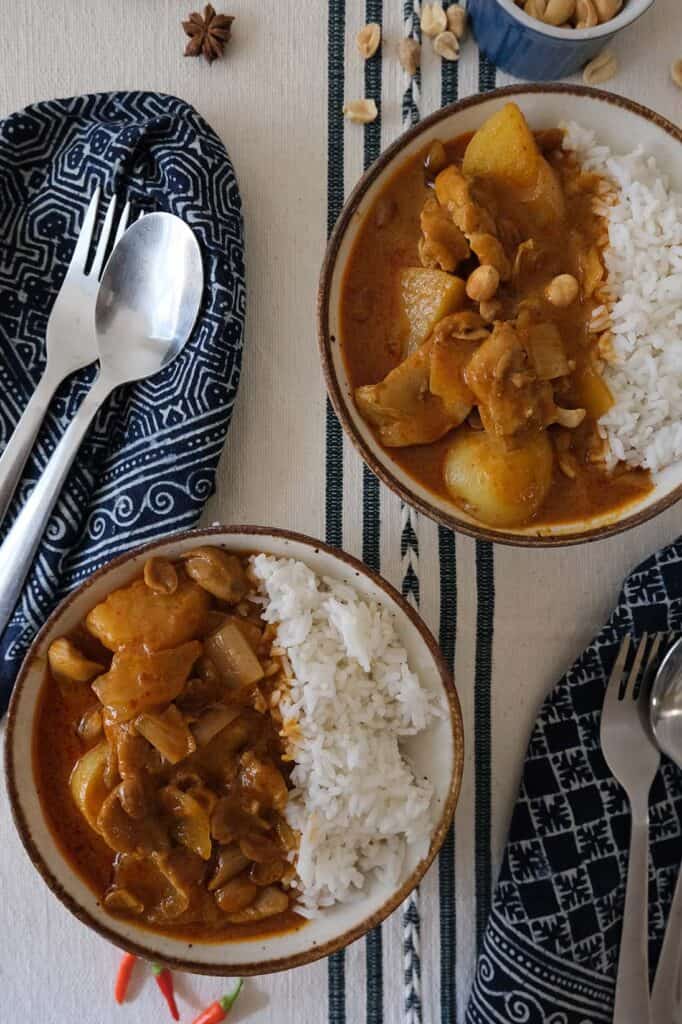 Thai Chicken Massaman Curry Recipe served in bowls with rice, topped with crunchy roasted peanuts