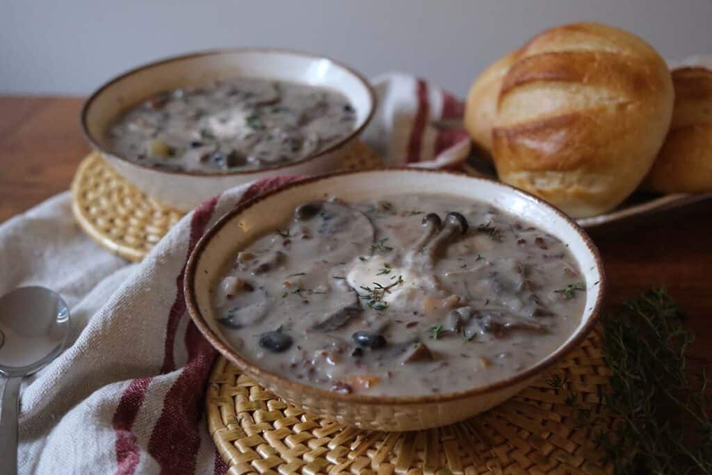 Side view of creamy wild mushroom soup recipe with wild rice and mushrooms, served warm with crusty rolls.