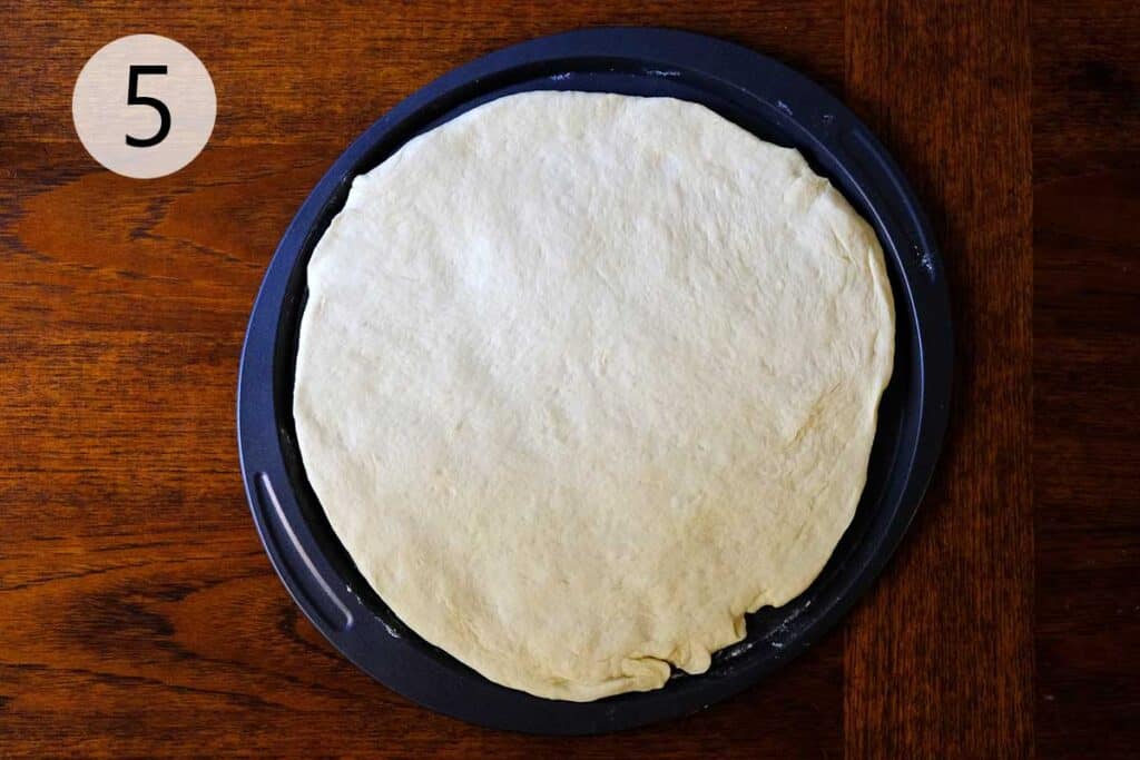 Stretching and shaping thin crust pizza dough into a 14-inch round, ready to add toppings for homemade pizza.