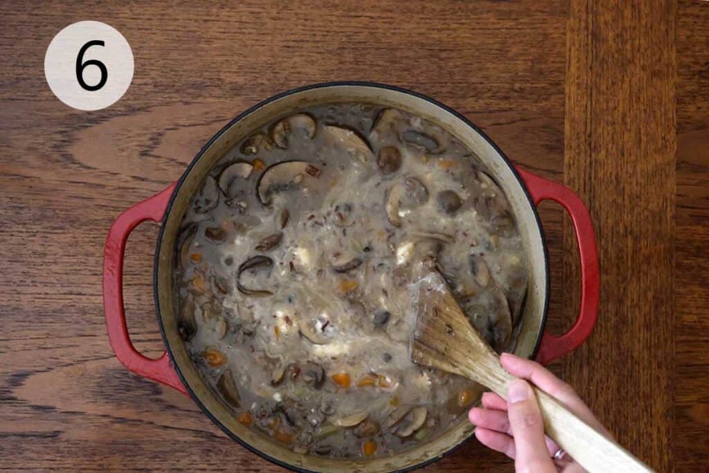 Sour cream being stirred into the finished wild mushroom soup to make it creamy and smooth before serving.