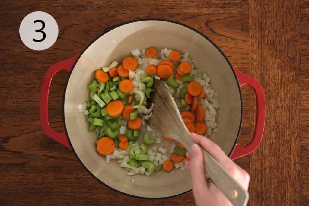 Onion, carrots, and celery sautéing in olive oil in a large pot for Turkey Meatball Soup Recipe.