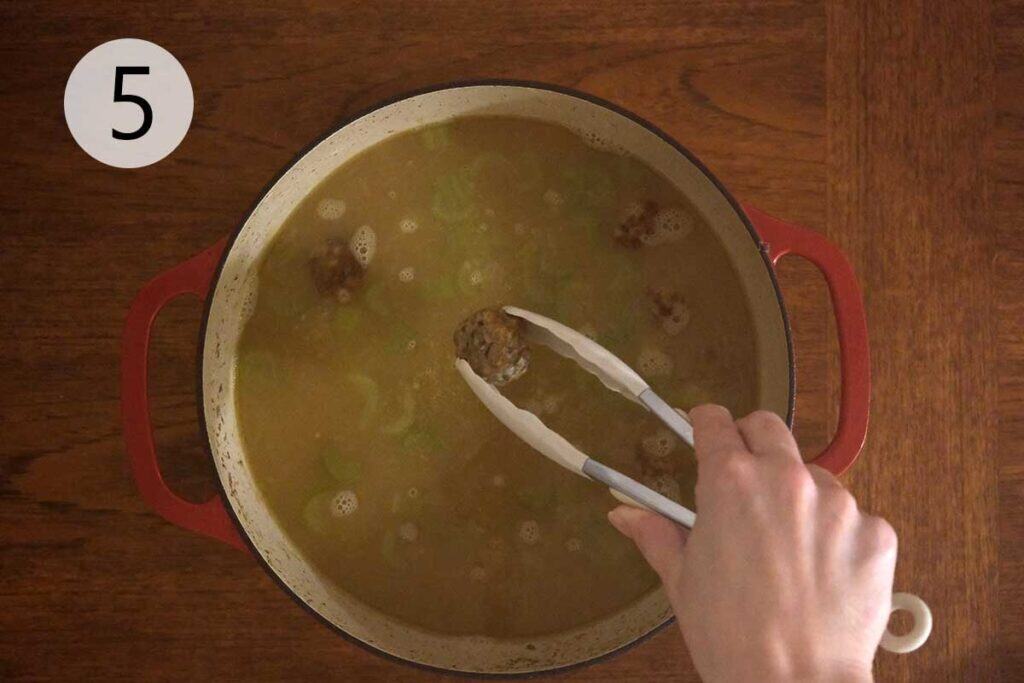 Cooked turkey meatballs added to simmering soup in pot for Turkey Meatball Soup Recipe.
