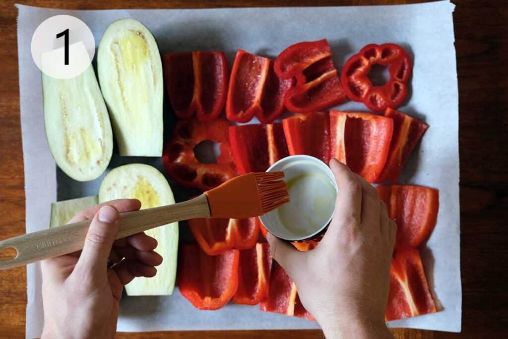 Ajvar recipe step 1 sliced red bell peppers and eggplant brushed with olive oil on a baking sheet