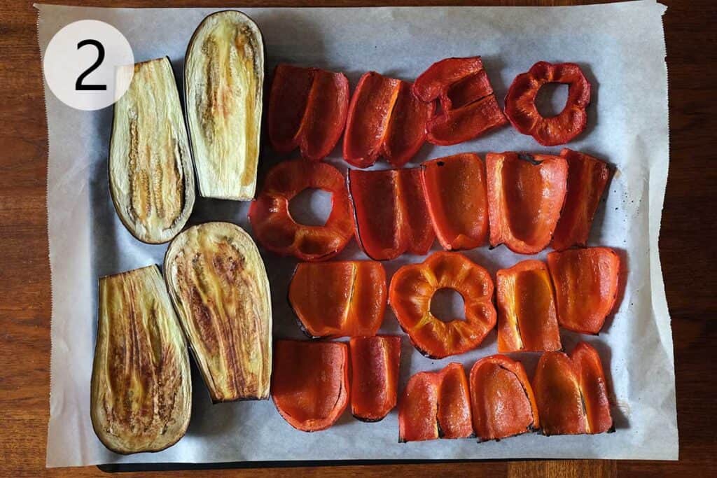 Ajvar recipe step 2 roasted red peppers and eggplant with charred skins on a baking sheet